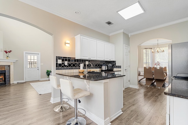 1190 Witshire Ct, Fort Walton Beach, FL 32547 - kitchen with arched walkways, light wood-style flooring, white cabinetry, crown molding, and decorative backsplash