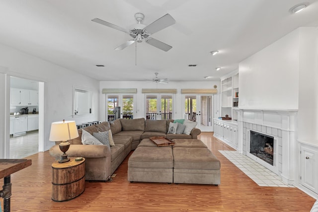 84 Old Miller Pl, Santa Rosa Beach, FL 32459 - living area with a ceiling fan, light wood-style flooring, a tile fireplace, and built in shelves