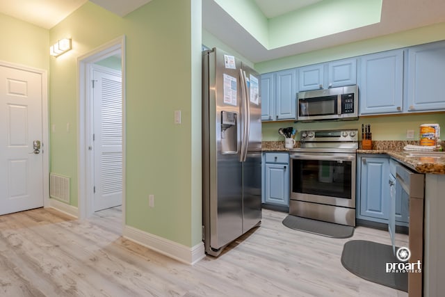 112 Seascape Dr Unit 704, Miramar Beach, FL 32550 - kitchen featuring appliances with stainless steel finishes, blue cabinetry, light wood-style floors, and baseboards