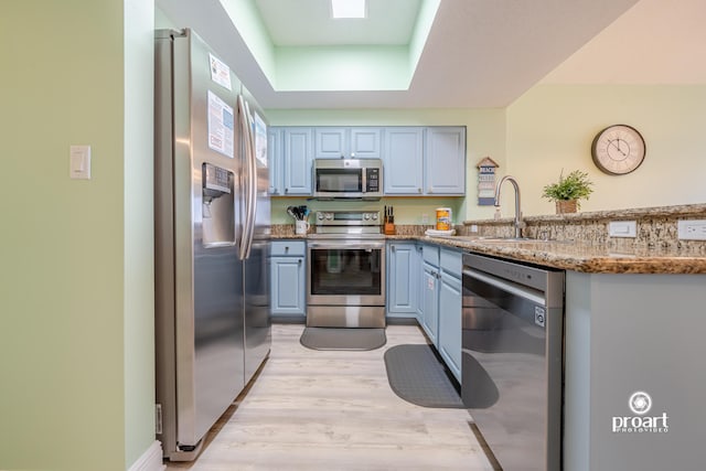 112 Seascape Dr Unit 704, Miramar Beach, FL 32550 - kitchen with appliances with stainless steel finishes, a sink, light wood-style floors, a peninsula, and stone counters