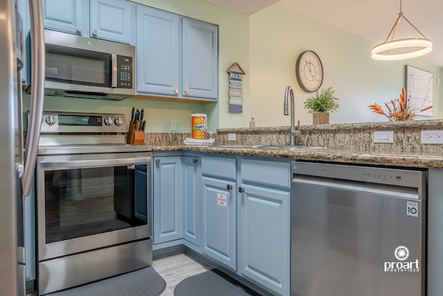 112 Seascape Dr Unit 704, Miramar Beach, FL 32550 - kitchen featuring stainless steel appliances, a sink, blue cabinetry, dark stone countertops, and light wood-type flooring