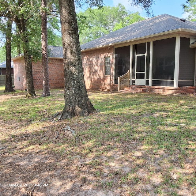 5848 Saratoga Dr, Crestview, FL 32536 - rear view of property with brick siding, a sunroom, a lawn, and a shingled roof