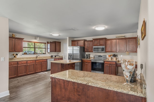 7302 Manatee St, Navarre, FL 32566 - kitchen with appliances with stainless steel finishes, a sink, wood finished floors, a peninsula, and light stone counters