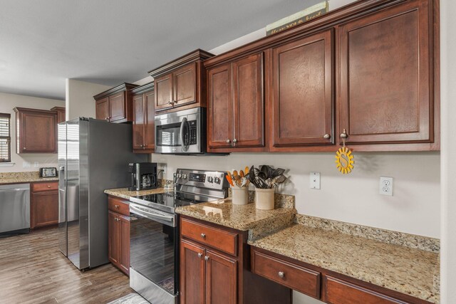 7302 Manatee St, Navarre, FL 32566 - kitchen with stainless steel appliances, light wood-style flooring, and light stone counters