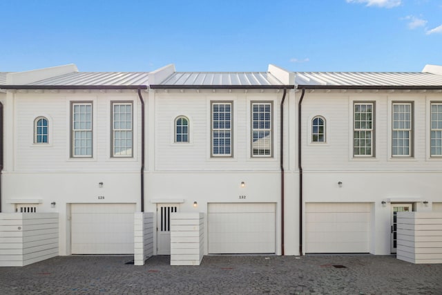 132 N Somerset St, Alys Beach, FL 32461 - rear view of house with an attached garage, a standing seam roof, driveway, metal roof, and stucco siding