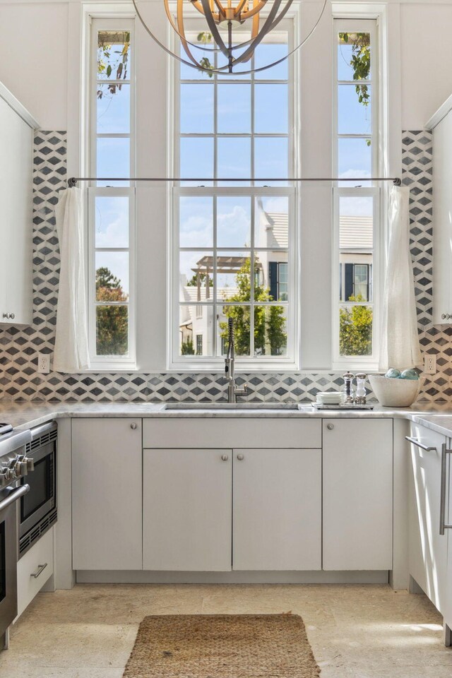 132 N Somerset St, Alys Beach, FL 32461 - kitchen with decorative backsplash, light countertops, a sink, and white cabinets