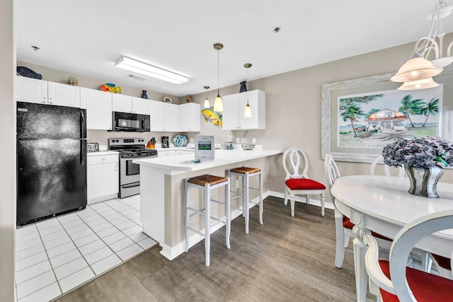 144 Spires Ln Unit 202, Santa Rosa Beach, FL 32459 - kitchen with black appliances, a peninsula, a kitchen bar, white cabinets, and light countertops