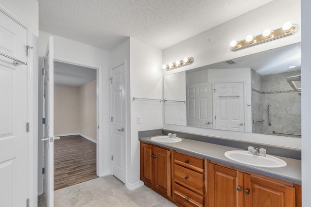 1184 Blackberry Cir, Baker, FL 32531 - bathroom with double vanity, a tile shower, a textured ceiling, baseboards, and tile patterned flooring