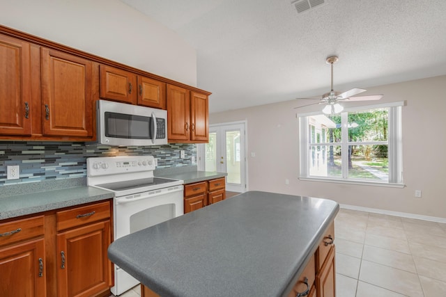 1184 Blackberry Cir, Baker, FL 32531 - kitchen with stainless steel microwave, white range with electric cooktop, decorative backsplash, brown cabinets, and a textured ceiling