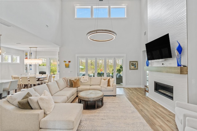 276 W Lafayette Rd, Inlet Beach, FL 32461 - living room featuring light wood-style floors, a tile fireplace, a high ceiling, a chandelier, and baseboards