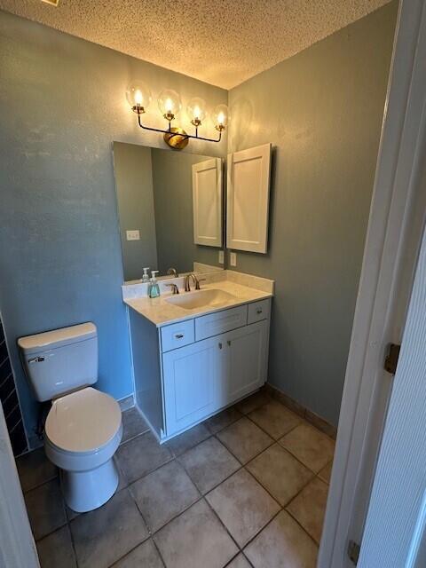 200 Sandestin Ln Apt 401, Miramar Beach, FL 32550 - bathroom with a textured ceiling, vanity, toilet, and tile patterned flooring