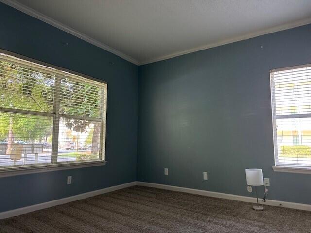 200 Sandestin Ln Apt 401, Miramar Beach, FL 32550 - spare room featuring dark colored carpet, crown molding, and baseboards