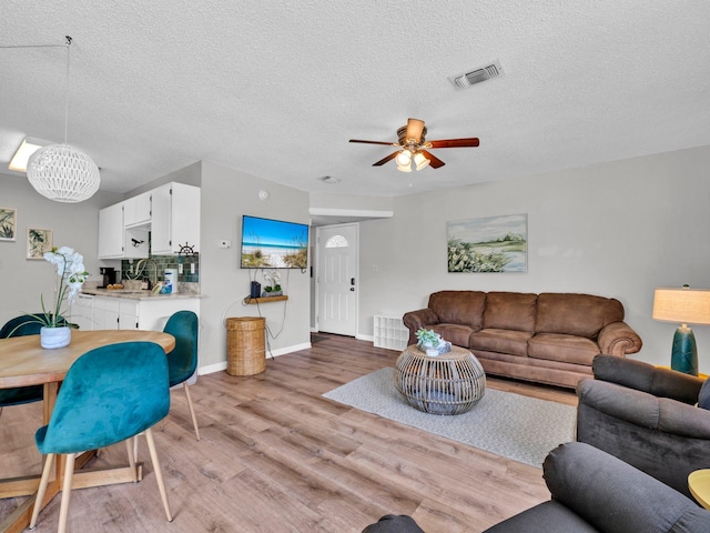 107 Surf Song Ln Unit A1, Miramar Beach, FL 32550 - living room with light wood-type flooring, a chandelier, a ceiling fan, a textured ceiling, and baseboards