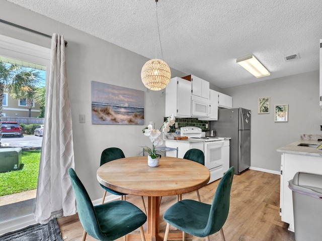 107 Surf Song Ln Unit A1, Miramar Beach, FL 32550 - dining room with a textured ceiling, a chandelier, light wood finished floors, and baseboards