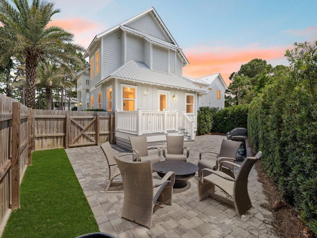 14 Bayshore Pines Ct, Miramar Beach, FL 32550 - back of property at dusk featuring a patio, a gate, board and batten siding, and an outdoor fire pit