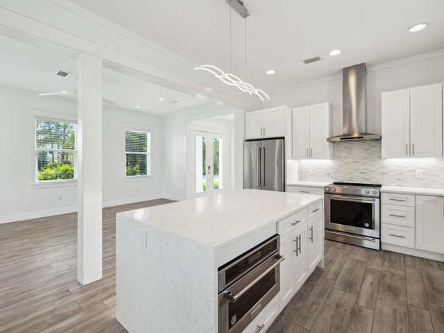 14 Bayshore Pines Ct, Miramar Beach, FL 32550 - kitchen with high end appliances, wall chimney exhaust hood, wood finished floors, decorative backsplash, and recessed lighting
