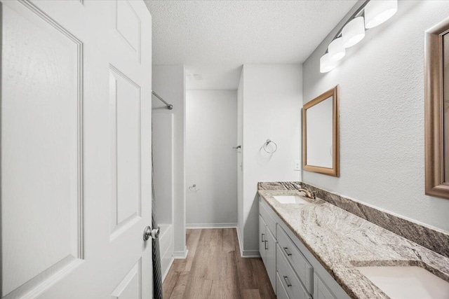 7319 Gordon Evans Rd, Navarre, FL 32566 - full bathroom with wood finished floors, double vanity, a textured ceiling, tub / shower combination, and baseboards