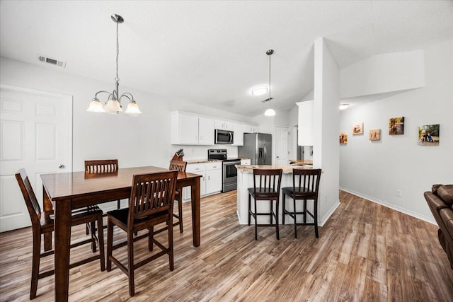7319 Gordon Evans Rd, Navarre, FL 32566 - dining space with lofted ceiling, a chandelier, light wood finished floors, and baseboards