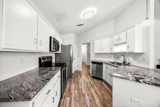 7319 Gordon Evans Rd, Navarre, FL 32566 - kitchen with appliances with stainless steel finishes, a sink, wood finished floors, white cabinets, and decorative backsplash