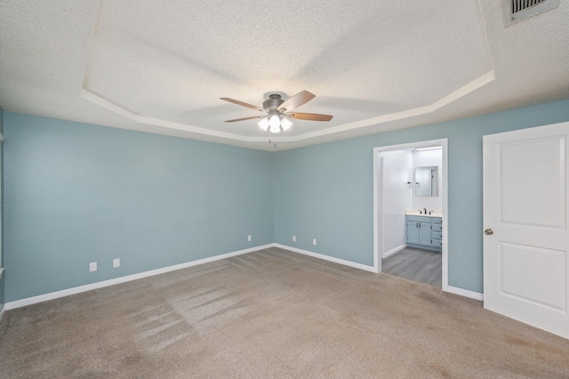 5903 Jack Stokes Rd, Baker, FL 32531 - unfurnished bedroom with a tray ceiling, a textured ceiling, carpet, connected bathroom, and ceiling fan