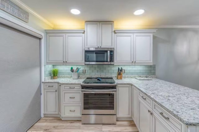 2800 Scenic Gulf Dr Unit 32, Miramar Beach, FL 32550 - kitchen with appliances with stainless steel finishes, decorative backsplash, crown molding, a peninsula, and light wood finished floors