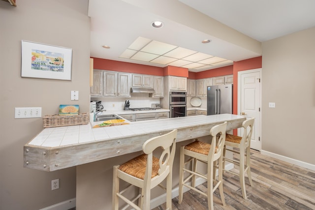 9815 US Highway 98 Unit 34, Miramar Beach, FL 32550 - kitchen featuring a sink, tile counters, stainless steel appliances, under cabinet range hood, and a peninsula