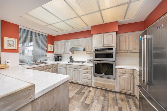 9815 US Highway 98 Unit 34, Miramar Beach, FL 32550 - kitchen with stainless steel appliances, a sink, tile counters, under cabinet range hood, and light wood finished floors