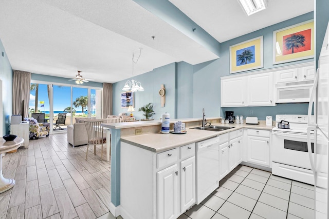 550 Tops L Beach Blvd # 102, Miramar Beach, FL 32550 - kitchen featuring white appliances, a sink, a peninsula, open floor plan, and white cabinets
