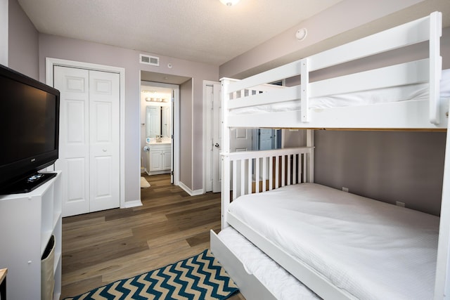 376 Santa Rosa Blvd Unit 101, Fort Walton Beach, FL 32548 - bedroom with wood finished floors, baseboards, a textured ceiling, multiple closets, and a sink