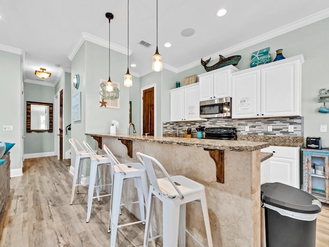 216 Tahitian Way, Destin, FL 32541 - kitchen with stainless steel microwave, a kitchen bar, tasteful backsplash, crown molding, and light wood-type flooring
