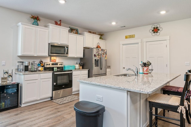 125 Hobson Ave, Crestview, FL 32539 - kitchen featuring appliances with stainless steel finishes, a sink, beverage cooler, a kitchen bar, and light wood-style floors