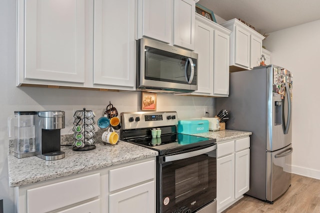 125 Hobson Ave, Crestview, FL 32539 - kitchen with appliances with stainless steel finishes, light wood-style floors, white cabinets, and light stone countertops
