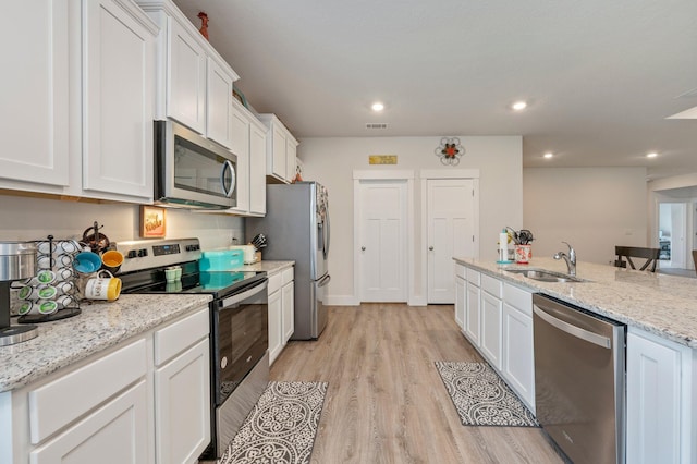 125 Hobson Ave, Crestview, FL 32539 - kitchen with appliances with stainless steel finishes, white cabinetry, a sink, light wood-style flooring, and light stone counters