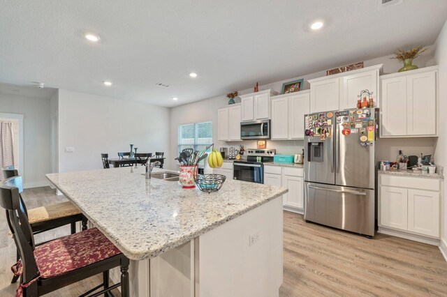 125 Hobson Ave, Crestview, FL 32539 - kitchen featuring stainless steel appliances, a breakfast bar area, white cabinets, an island with sink, and a sink