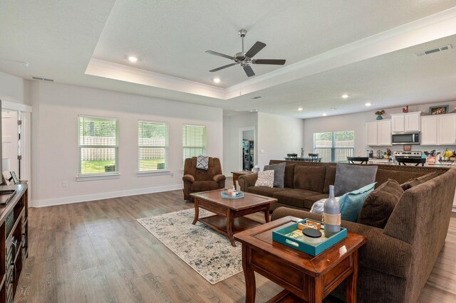 125 Hobson Ave, Crestview, FL 32539 - living room with light wood finished floors, a ceiling fan, a tray ceiling, recessed lighting, and baseboards