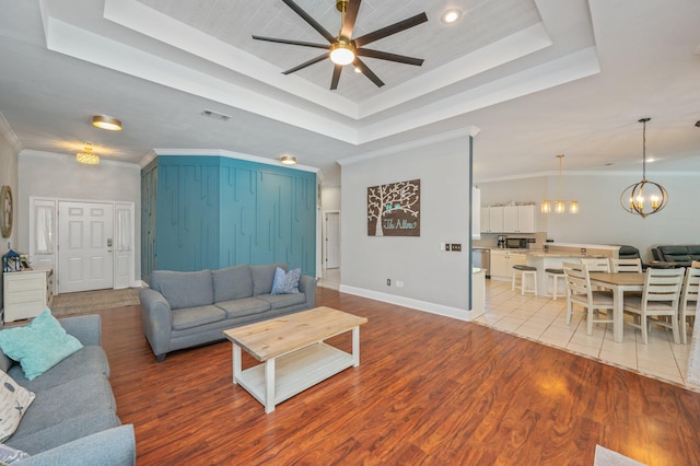 4680 Lovegrass Ln, Crestview, FL 32539 - living area featuring a tray ceiling, ceiling fan, light wood-style flooring, a chandelier, and ornamental molding