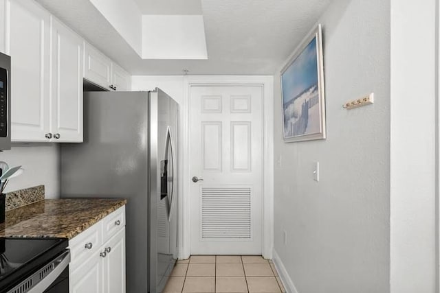 14701 Front Beach Rd Unit 1331, Panama City Beach, FL 32413 - kitchen with white cabinets, light tile patterned floors, dark stone counters, baseboards, and stainless steel fridge
