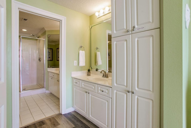 8499 Gulf Blvd Unit 303, Navarre, FL 32566 - bathroom with a textured ceiling, a stall shower, vanity, wood finished floors, and crown molding