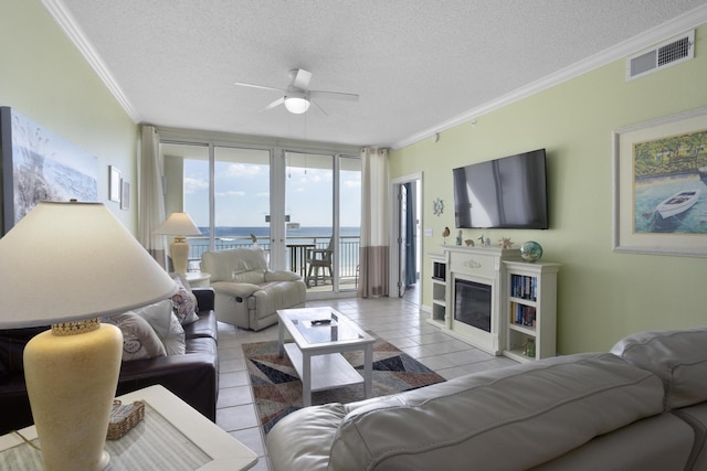 8499 Gulf Blvd Unit 303, Navarre, FL 32566 - living room with ceiling fan, ornamental molding, a textured ceiling, tile patterned flooring, and a glass covered fireplace