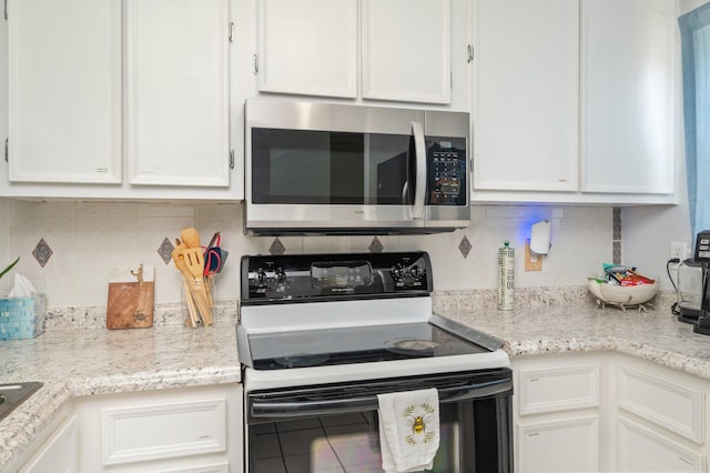 208 3rd St Unit J, Fort Walton Beach, FL 32548 - kitchen with stainless steel microwave, range with electric cooktop, white cabinets, and backsplash