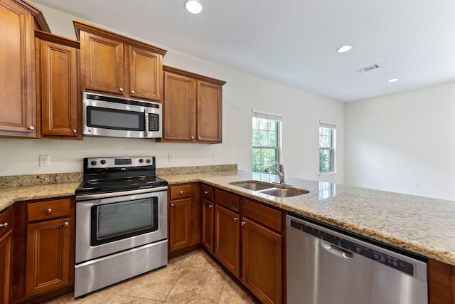 2131 Wilsons Plover Cir, Navarre, FL 32566 - kitchen with appliances with stainless steel finishes, a sink, light stone counters, brown cabinetry, and recessed lighting