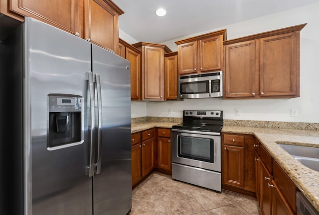 2131 Wilsons Plover Cir, Navarre, FL 32566 - kitchen featuring appliances with stainless steel finishes, brown cabinets, light stone counters, and recessed lighting