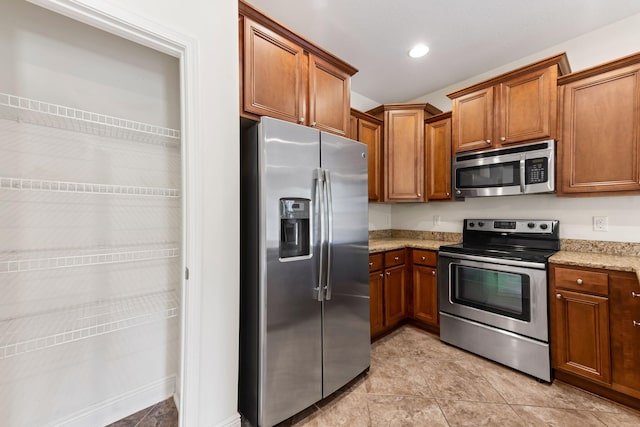 2131 Wilsons Plover Cir, Navarre, FL 32566 - kitchen featuring stainless steel appliances, brown cabinetry, and light stone counters