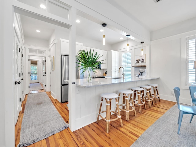 125 Silver Laurel Way, Santa Rosa Beach, FL 32459 - kitchen with light wood-style floors, a peninsula, white cabinetry, a breakfast bar, and recessed lighting