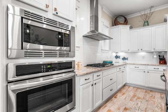 62 Dune Comet Ln Unit B, Inlet Beach, FL 32461 - kitchen featuring appliances with stainless steel finishes, wall chimney exhaust hood, ornamental molding, backsplash, and white cabinets