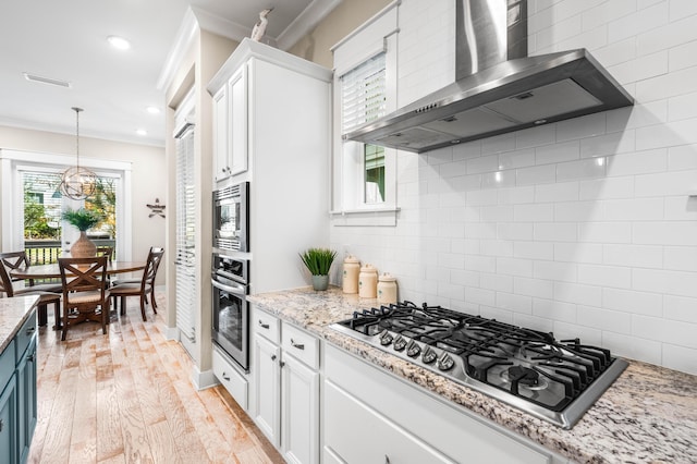 62 Dune Comet Ln Unit B, Inlet Beach, FL 32461 - kitchen with wall chimney exhaust hood, stainless steel appliances, crown molding, a chandelier, and white cabinets