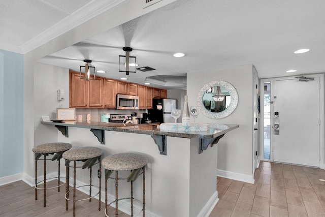 291 Scenic Gulf Dr Unit 201, Miramar Beach, FL 32550 - kitchen featuring stainless steel appliances, recessed lighting, light wood-style floors, a kitchen breakfast bar, and brown cabinets
