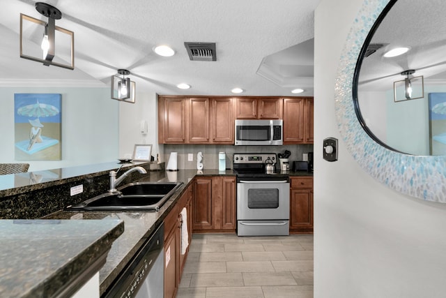 291 Scenic Gulf Dr Unit 201, Miramar Beach, FL 32550 - kitchen with appliances with stainless steel finishes, a sink, crown molding, brown cabinets, and dark stone counters