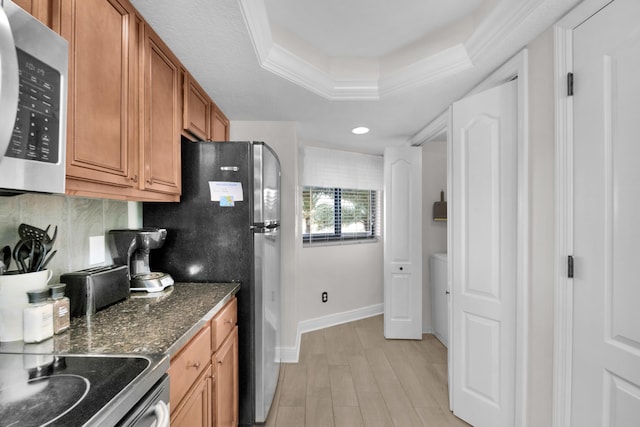 291 Scenic Gulf Dr Unit 201, Miramar Beach, FL 32550 - kitchen featuring appliances with stainless steel finishes, brown cabinetry, a tray ceiling, light wood-style floors, and baseboards