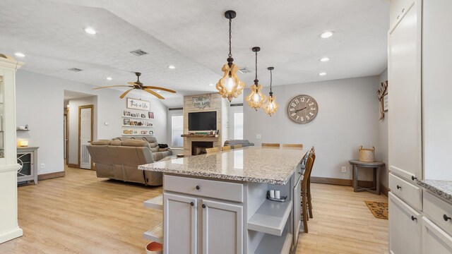 241 Mullet Dr, Freeport, FL 32439 - kitchen with ceiling fan, a large fireplace, open shelves, light wood-style flooring, and hanging light fixtures